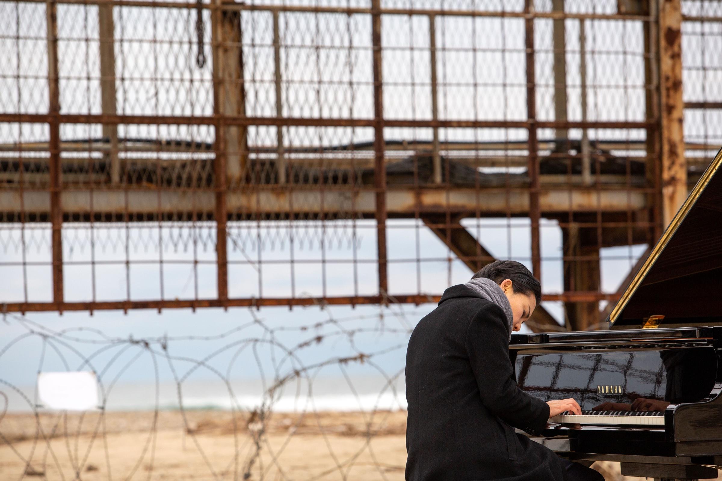 Mijung IM performing beside a rusted structure on the DMZ coastline
